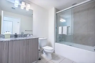 a bathroom with a toilet and a glass shower at Stunning Apartment in Downtown Doral in Miami