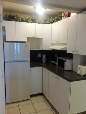 a kitchen with white cabinets and a refrigerator at Castle 727 Studio with balcony and Ocean view, Pool, Tennis, Beach Access, Free Parking in Miami Beach
