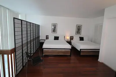 two beds in a room with wooden floors and white walls at Castle B6 in Miami Beach