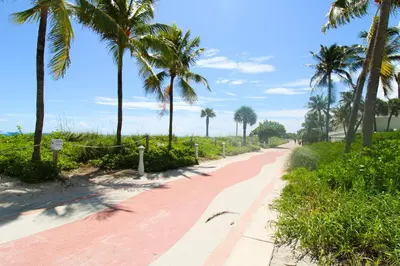 a red brick path with palm trees on the side at Castle PH12 Spacious Bay View Penthouse, Pool, Tennis, Free Parking in Miami Beach