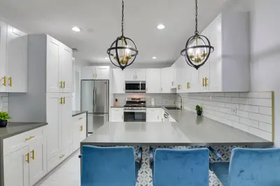 a kitchen with white cabinets and blue chairs at Luxe Miami Home Outdoor Kitchen, Gas Grill! in Miami Gardens