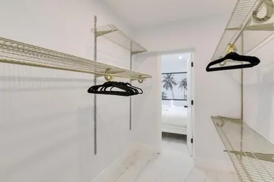 a white room with two racks of shoes at Luxe Miami Home Outdoor Kitchen, Gas Grill! in Miami Gardens