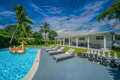 a swimming pool with chaise lounges and a pool noodleinger in at New Tropical Oasis Retreat in Miami in Miami
