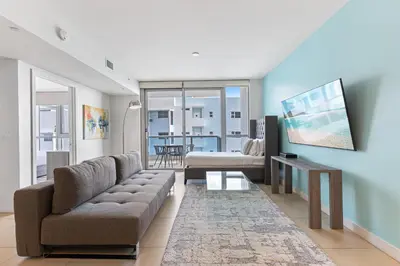 a living room with a couch and a tv at Dharma Home Suites Miami Beach at Monte Carlo in Miami Beach