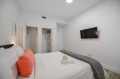 a white bedroom with a bed and a tv at Charming Apt Near to Stadium LoanDepot Park in Miami