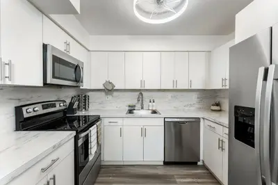 a kitchen with white cabinets and a stainless steel refrigerator at Sunrise Getaway in Sunrise
