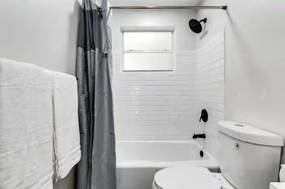 a white bathroom with a toilet and a window at Mia Airport 1b Apt with desk Virg 9 in Miami