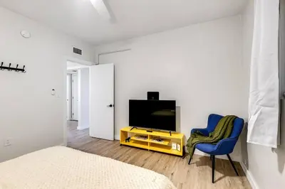 a bedroom with a television and a blue chair at Stylish 2BR central Fast Wi fi virg2 in Miami