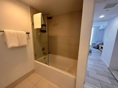 a bathroom with a tub and a shower with towels at High-End Miami Condo, Ocean Views & Kitchen -A in Hallandale Beach