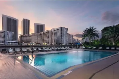 a large swimming pool with chairs and a city skyline at Disfruta como en Miami, hermoso estudio para 4 in BeachWalk in Hallandale Beach