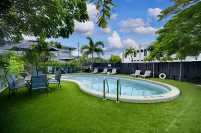 a swimming pool in a yard with chairs and a table at Holiday Park Apartments by Lowkl in Fort Lauderdale
