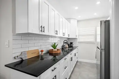 a kitchen with white cabinets and a black counter top at Holiday Park Apartments by Lowkl in Fort Lauderdale