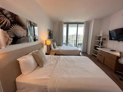 a bedroom with a large white bed and a television at Incredible Miami Studio with 2 full Beds, 1 Bath, Stylish Stay in Hallandale Beach