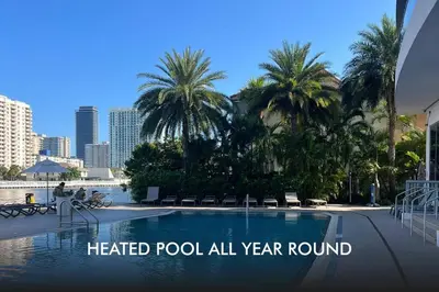 a heated pool all year round with palm trees and buildings at Incredible Miami Studio with 2 full Beds, 1 Bath, Stylish Stay in Hallandale Beach