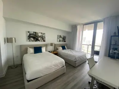 a bedroom with two beds and a desk and a window at Chic Studio in Miami Sleeps 4, Full Bath, Great Vibe in Hallandale Beach