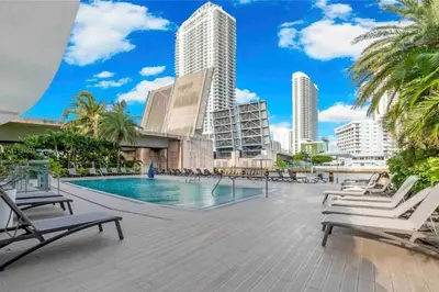 a swimming pool with chaise lounge chairs and buildings at Oceanfront Studio with Beach, Pool & Restaurants in Hallandale Beach