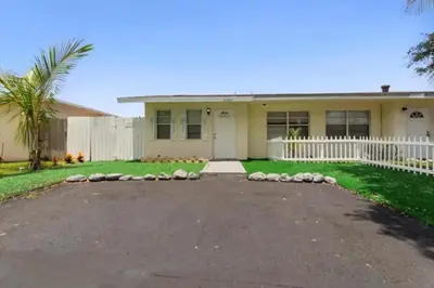 a house with a white fence and a driveway at Lakeside Retreat with Private Yard & Kayak in Fort Lauderdale