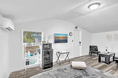 a white living room with a table and a chair at Boutique Vacation Studio - Beach, Mall, Casino Hn2 in Hallandale Beach