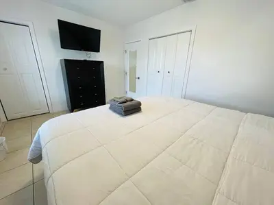 a large white bed in a white room with a television at Coral Gables Home with POOL Near Airport. King beds in Miami