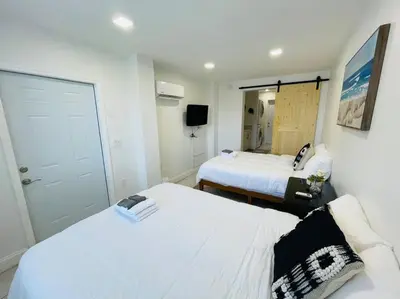 a hotel room with two beds and a mirror at Coral Gables Home with POOL Near Airport. King beds in Miami