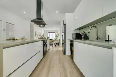 a kitchen with white cabinets and a wooden floor at Radiance - Modern Design, Poolside Escape in Miami