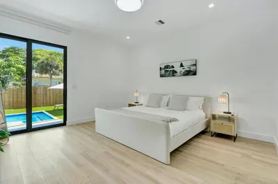 a white bedroom with a bed and a pool at Radiance - Modern Design, Poolside Escape in Miami
