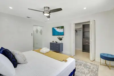 a white bedroom with a bed and a ceiling fan at The Gardens - Luxe, Pool, Mins to Hard Rock Stadium in Miami Gardens