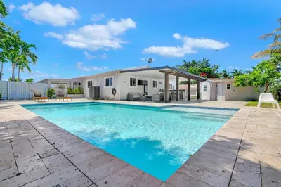 a swimming pool in front of a house at The Gardens - Luxe, Pool, Mins to Hard Rock Stadium in Miami Gardens