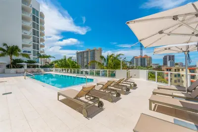 a patio with a pool and lounge chairs and an umbrella at Tiffany Hazel - Rooftop Pool, Gym, & Walk to Beach in Fort Lauderdale