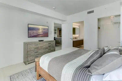 a bedroom with a bed and a television on a wall at Tiffany Blanca - Rooftop Pool, Gym, & Walk to Beach in Fort Lauderdale