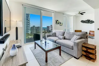 a living room with a couch and a glass table at Tiffany Blanca - Rooftop Pool, Gym, & Walk to Beach in Fort Lauderdale