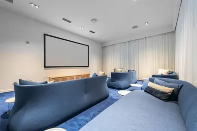 a living room with blue couches and a projection screen at Tiffany Sage - Rooftop Pool, Gym, & Walk to Beach in Fort Lauderdale
