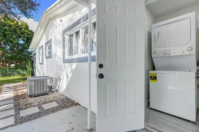 a front door of a tiny house with a washer and dryer at Renovated professional design, grill lake view! in Hallandale Beach