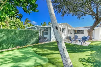 a house with a green yard with a tree at Renovated professional design, grill lake view! in Hallandale Beach