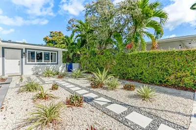 a home with a garden and a house at Renovated professional design, grill lake view! 1 in Hallandale Beach
