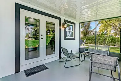 a porch with chairs and a table and windows at Renovated professional design, grill lake view! 1 in Hallandale Beach