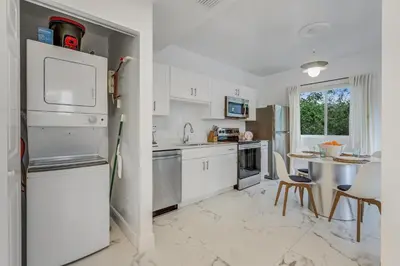 a kitchen with white cabinets and a table and a refrigerator at ArTease5 - stylish, near Wynwood Walls & restaurants in Miami