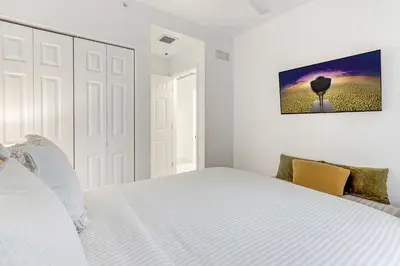 a white bedroom with a white bed and a painting on the wall at ArTease5 - stylish, near Wynwood Walls & restaurants in Miami