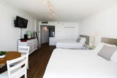 a white bedroom with two beds and a table at Castle 1029 Balcony studio with Ocean View, Pool, Tennis and Free Parking in Miami Beach