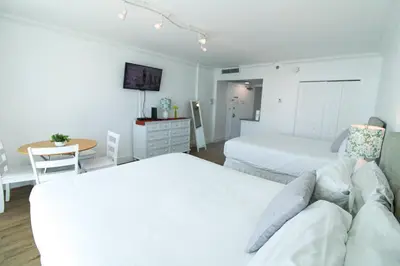 a white bedroom with two beds and a table at Castle 1029 Balcony studio with Ocean View, Pool, Tennis and Free Parking in Miami Beach