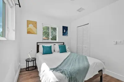 a white bedroom with a large bed with blue pillows at Escape to Private Poolside Bliss in Hollywood