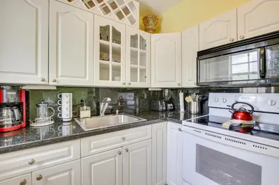 a kitchen with white cabinets and a sink and a stove at 4 Mi to Beach Hollywood Home with Patios! in Hollywood
