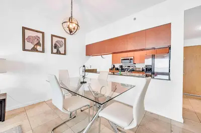 a dining room with a glass table and white chairs at Modern 1 Bed in the Heart of Brickell With Free Parking in Miami