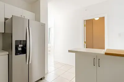 a white kitchen with a stainless steel refrigerator at Pavilion - Stunning bay view in Miami Beach