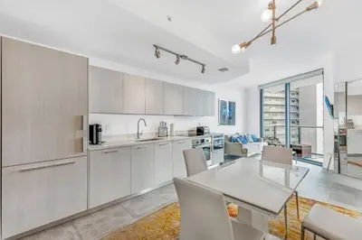 a kitchen with white cabinets and a table and chairs at Exclusive High-Rise Edgewater 1BD - Tennis & Sauna in Miami