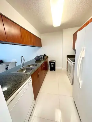 a kitchen with a sink and a refrigerator at 36th floor Brickell bay view 1BR 2 Queens and Sofa Bed in Miami