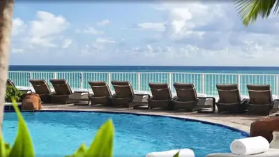 a pool with chairs and the ocean in the background at Luxurious Beach Resort Balcony in Sunny Isles Beach