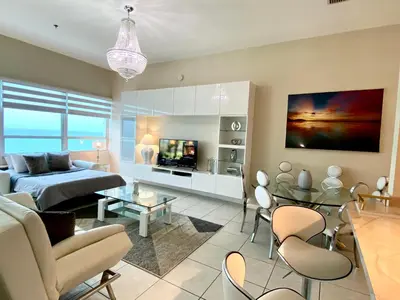 a living room with a bed and a couch and a table at Large beautiful penthouse ocean front with beach access and free parking in Miami Beach in Miami Beach