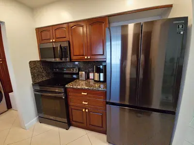 a kitchen with wooden cabinets and a stainless steel refrigerator at Quiet Oasis Steps From Shops with Golf View-CS61 in Hollywood