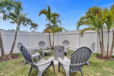 four chairs and a trash can in a yard with palm trees at Cozy Fun House 4 2 Aventura Stadium Beach in North Miami Beach